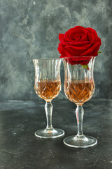 Close up two glasses of liquor and a rose on a black background.