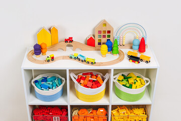White shelving with colorful storage baskets and transparent boxes in children room. Rainbow toys...