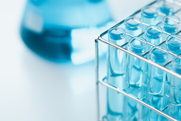 Test tubes and erlenmeyer flask filled with blue sample chemicals in chemistry science laboratory....