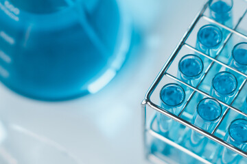 Test tubes and erlenmeyer flask filled with blue sample chemicals in chemistry science laboratory....