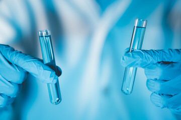 Scientist hand hold test tubes filled with blue sample chemicals in chemistry science laboratory....