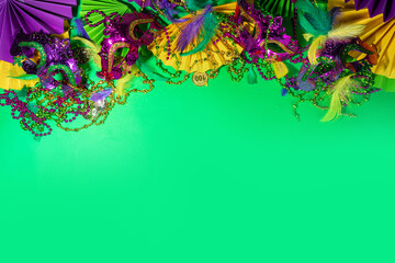 Mardi Gras colourful holiday greeting card background with festival masquerade accessories, decor, carnival mask, beads, feathers, fan on bright background traditional yellow purple green colors © ricka_kinamoto