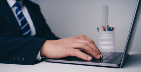 Close up Person hands typing on laptop keyboard in the office.