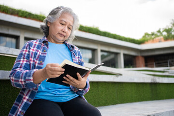 Mature adult student sitting in front off College building and reading school books after attending...