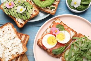 Different delicious sandwiches on light blue wooden table, flat lay