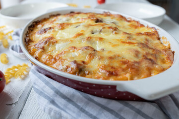 Closed casserole with cheese topping in baking dish on kitchen table
