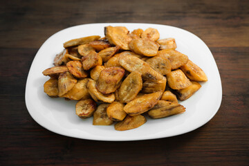 Tasty deep fried banana slices on wooden table