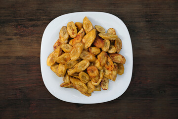 Tasty deep fried banana slices on wooden table, top view