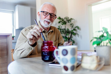 Senior Caucasian man painting at her home.