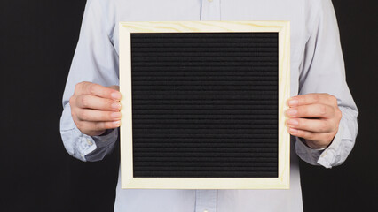 Man is holding a black letter board on black background.