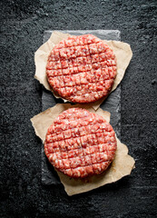 Raw burgers on paper.