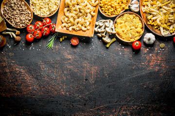 Assortment of different types of raw pasta with mushrooms, tomatoes and garlic.