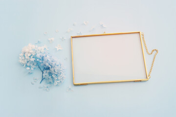 Top view image of blue dry flowers and empty gold photo frame with copy space over pastel...