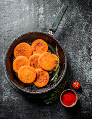 Fish cutlets in a old pan with the thyme and tomato sauce in a bowl.