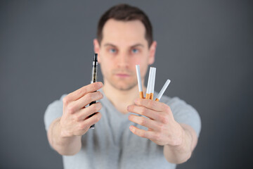 man holding an e-cig and cigarettes - obrazy, fototapety, plakaty
