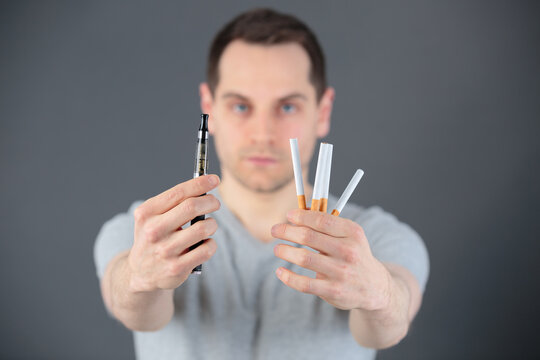 man holding an e-cig and cigarettes
