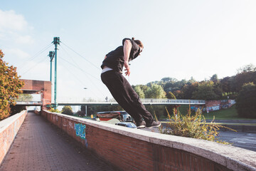 Young sportive athletic man doing parkour outdoors city jumping beyond obstacle