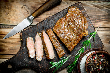 Sliced grilled beef steak with rosemary.