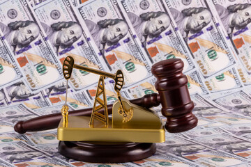 Judge's gavel and golden oil pump against the background of 100 US dollar bills