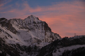 Sunlit pink clouds over Mount Arpelistock in winter.