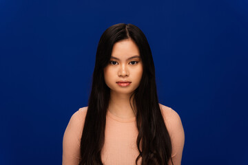 Long haired asian woman looking at camera isolated on navy blue