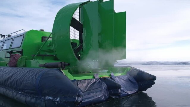 hovercraft with a running engine stands on the ice of Lake Baikal in winter. smoke is coming out of the exhaust pipe. an environmental problem with toxic gases. safe amphibious transport. closeup.
