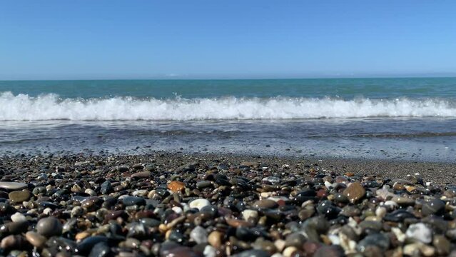 The calm sea floods the sea pebbles on the shore and the sound of the sea