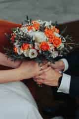 Bride and Groom holding Bouquet together with wedding rings on  their fingers