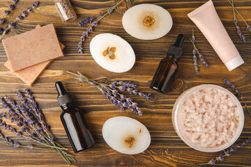 Essential oils, serum, scrub, handmade soap and lavender flowers on a brown textural background. Spa concept. Relaxation and relaxation.