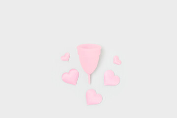 Pink menstrual cup and hearts confetti on a blue background. Zero waste period concept.