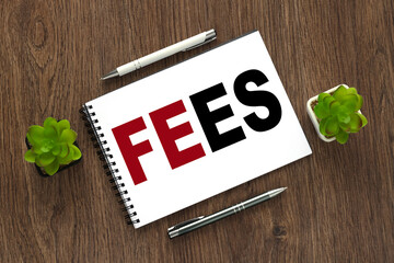 notepad with a spring near a plant in a pot. text on paper. Fees