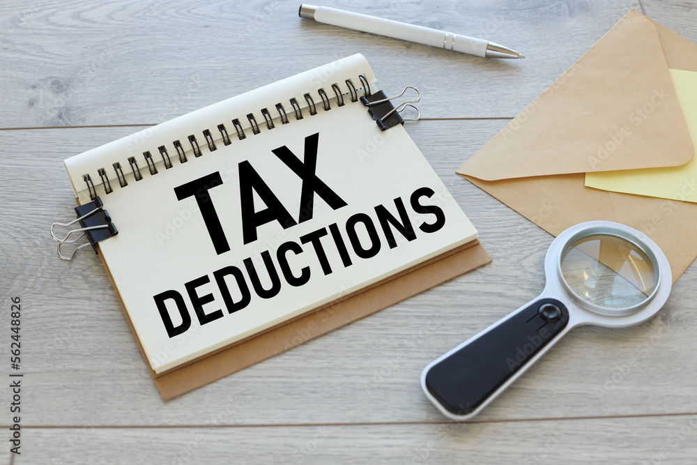 Poster tax deductions text on a notebook with a spring. notebook and magnifying glass