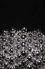 Vertical Photo Of Small Glittering Beads In A Bunch Over Black Background 
