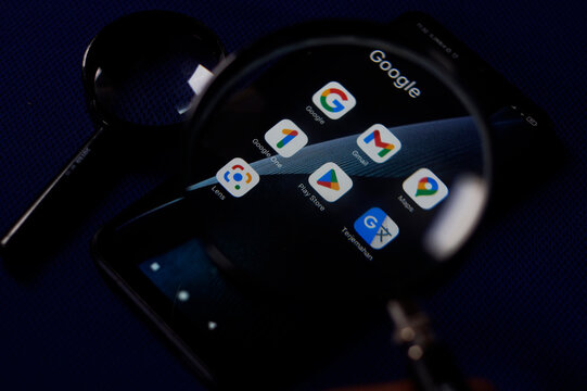 Closeup Google apps product icon on a smartphone screen through a magnifying glass. Wonosobo, Central Java, Indonesia January 17, 2023.