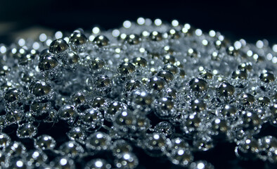 Shiny round elements glowing under light on a black background 