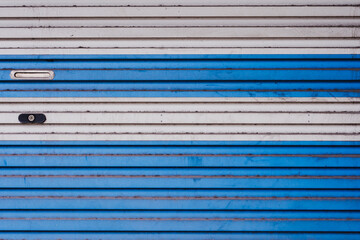 The texture of white and blue metallic roller shutter door in front of the factory