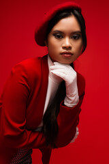 Portrait of brunette asian model with makeup and stylish outfit isolated on red