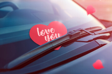 Red heart with text I love you. Paper heart on the windshield of the car under the brush. The...