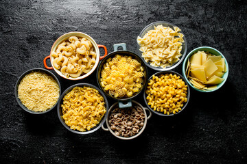 The range of different types of dry pasta in different bowls.