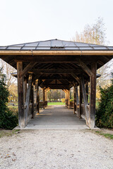 Little wooden and roofed bridge across the little creek of the park