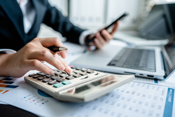 Businesswomen or Accountants use a calculator to work with financial statements and analyze company financial reports. investment, balance sheets, taxes, planning and business strategies concept.