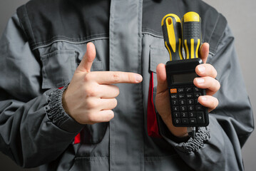 Calculation of the cost of repair concept. Service worker holds screwdrivers and calculator close...