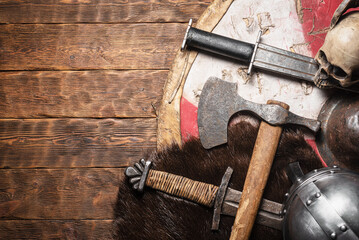 Old battle swords, axe and shield on the wooden table top view background with copy space.
