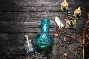 Old magic book and dry natural herbs and remedy bottle on the wooden table flat lay background with...
