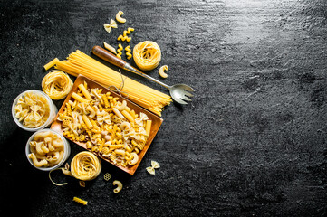 Different types of dry pasta on the plate and bowls.