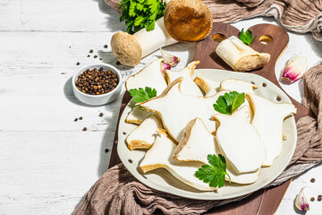 Fresh Pleurotus eryngii mushrooms on wooden background. Raw king oyster eringi with spices and herbs