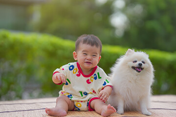 The Happy child with the dog lying on the mat in the garden. Baby boy having fun with the dog....