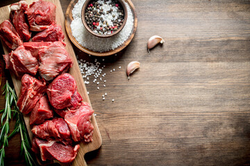 Cut raw beef with garlic cloves,rosemary and seasonings in bowls.