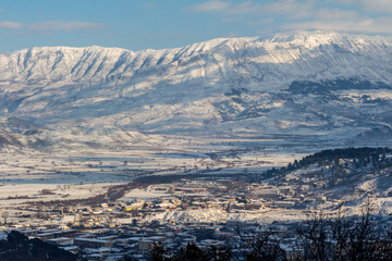 Winter landscape, covered with snow. Panorama of Gjirokastër (Gjirokaster), Albania, with the gorgeous Mali i Gjerë mountains that surround the city.