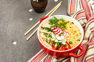 Asian noodles with chicken, vegetables, and herbs in a red bowl. Traditional Japanese soup